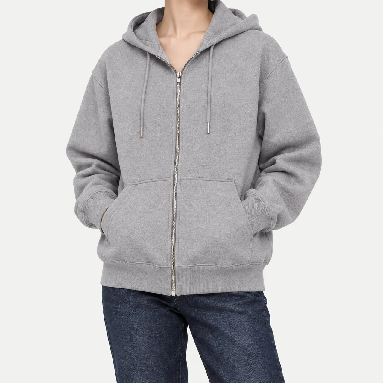 A model wearing a gray heavyweight French terry zip-up hoodie with hands in the pockets