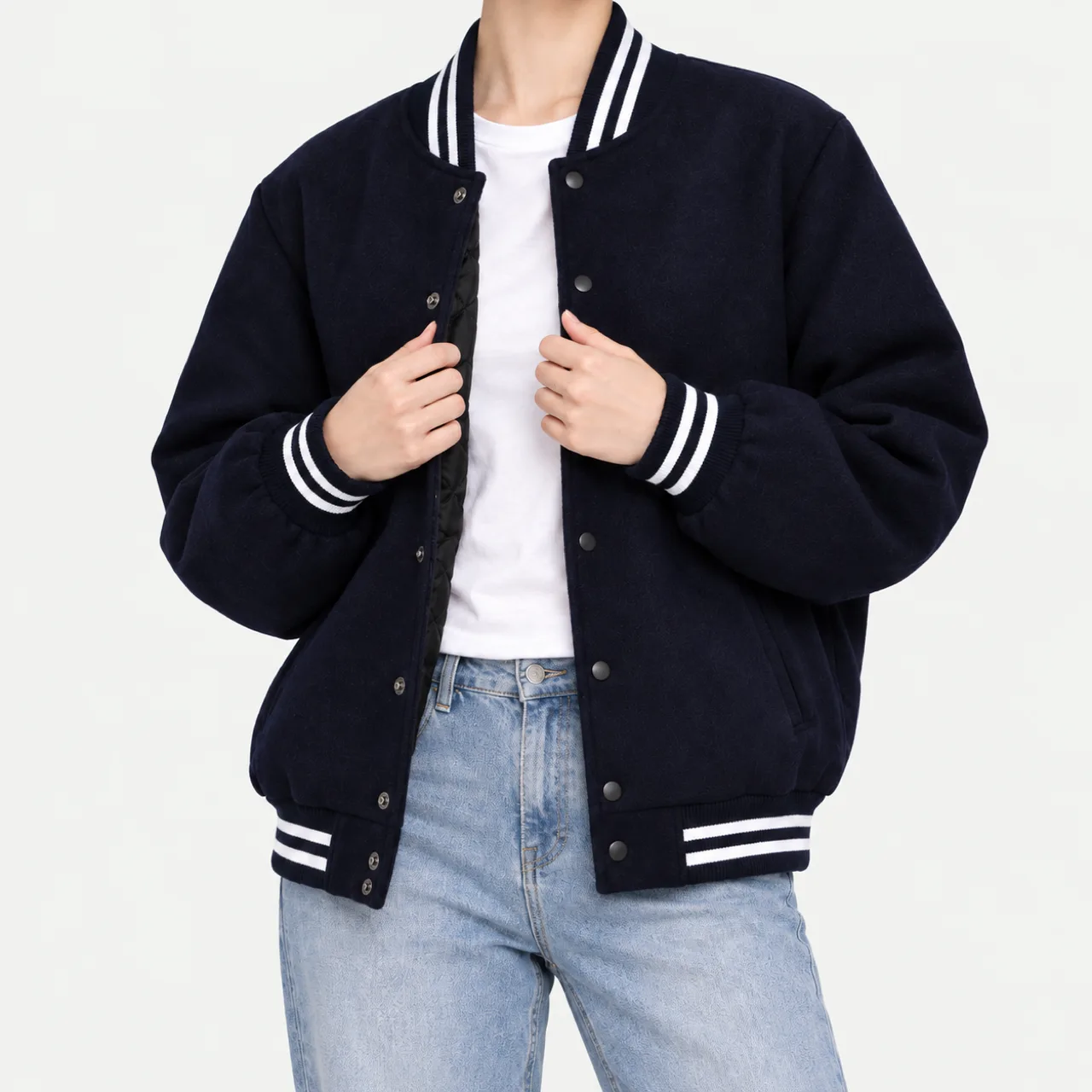 A model wearing an open dark navy stadium jacket and holding the front placket