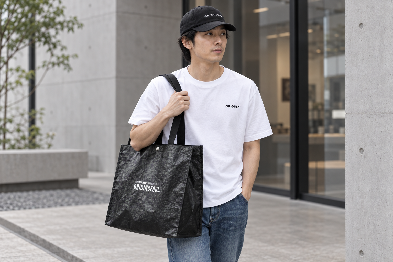 오리진X 티셔츠와 모자, 청바지 차림으로 타포린백을 어깨에 멘 성인 모델