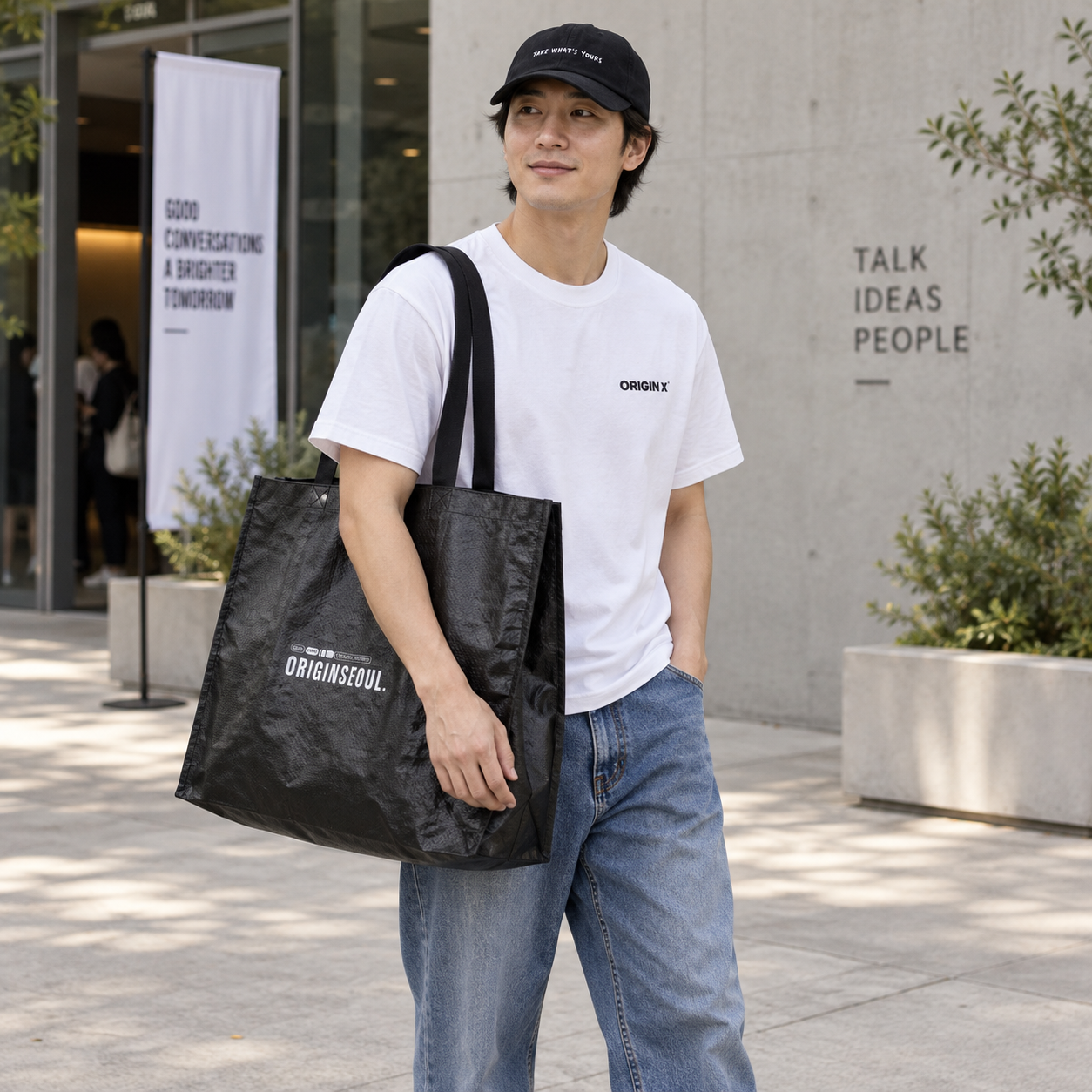 오리진X 화이트 티셔츠와 모자, 청바지 차림으로 타포린백을 어깨에 멘 사용 장면