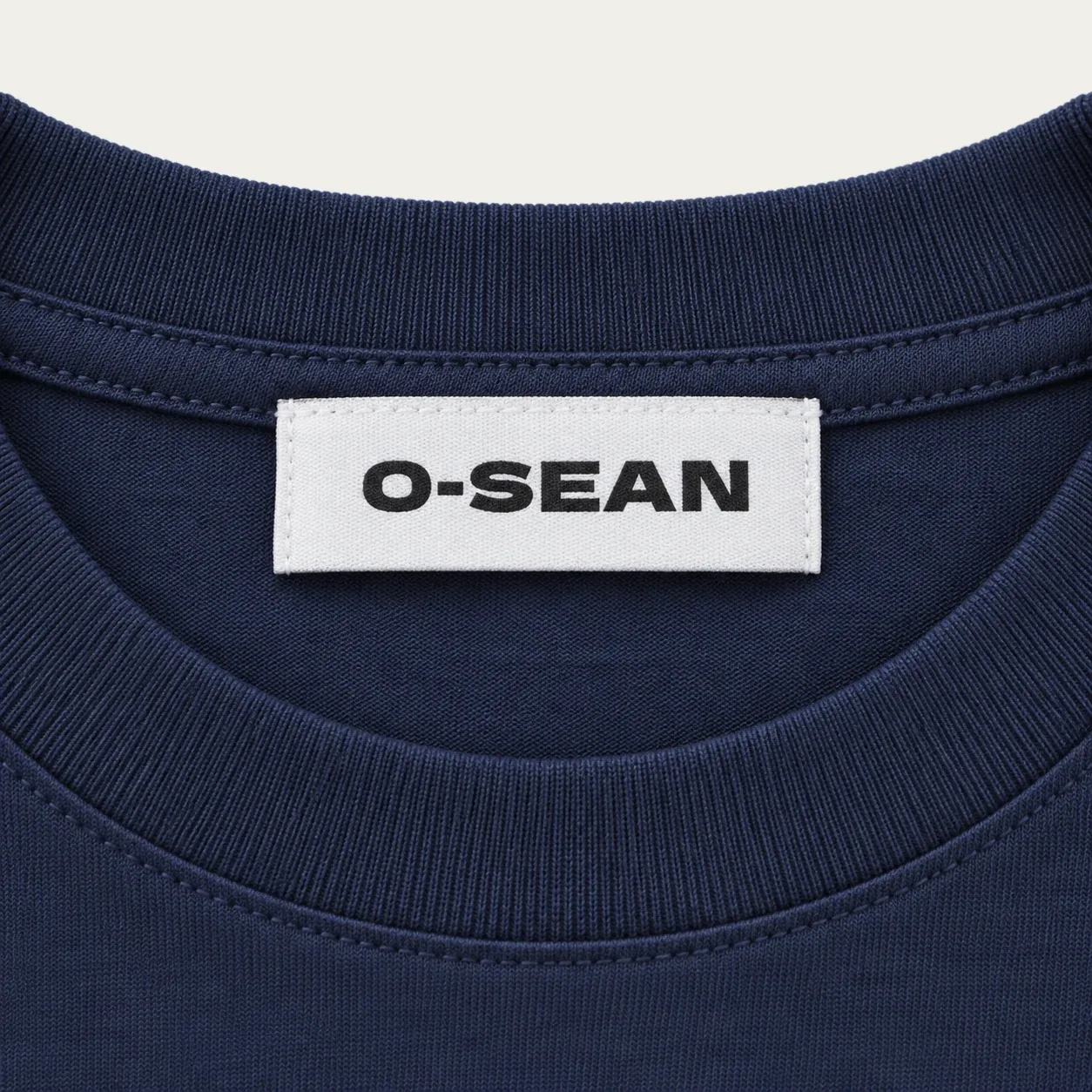 네이비 반팔 티셔츠 목뒤에 O-SEAN 직조라벨을 박음질한 모습