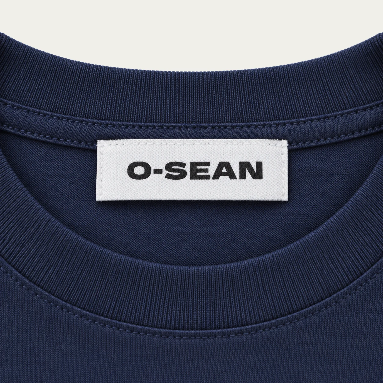O-SEAN woven label sewn on the back neck of a navy short-sleeve T-shirt