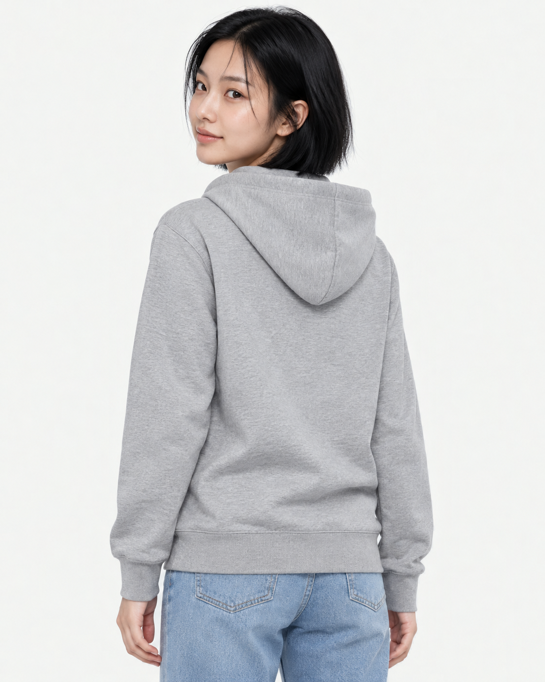 Back view of a woman wearing a Moku gray light hoodie in M, looking over her shoulder, hood down over a blank back
