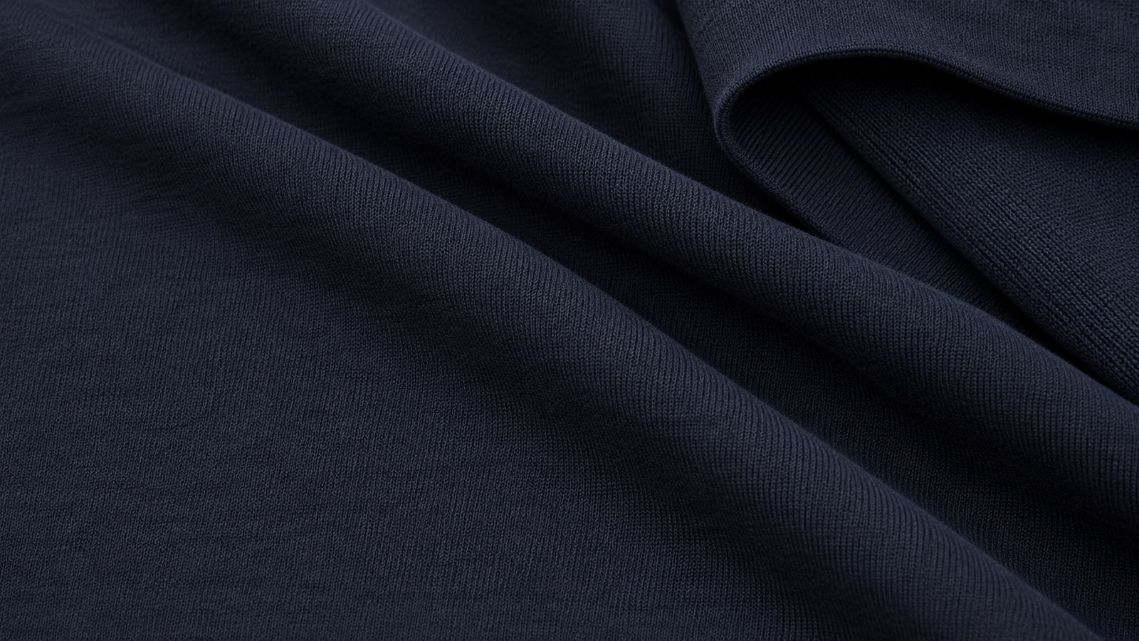 Close-up of loosely folded navy double-knit fabric showing the tight weave and the smooth, unbrushed inside