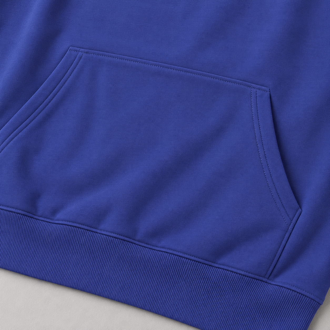 Close-up of the front pocket and its angled hand openings on a cobalt blue hoodie