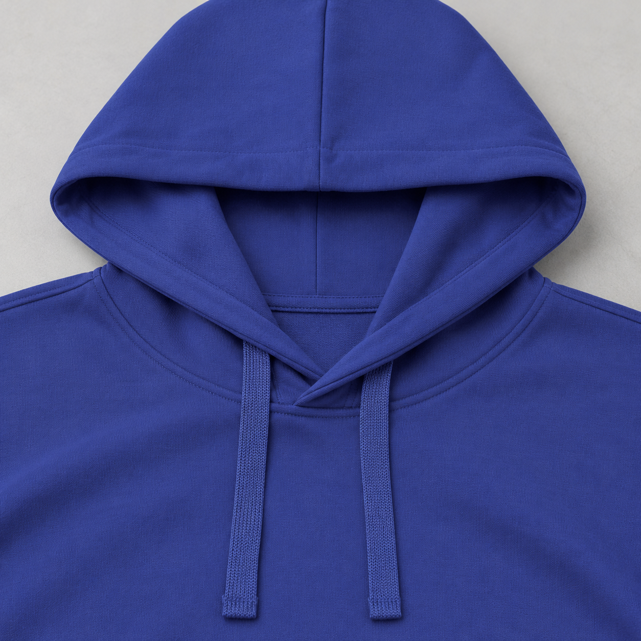 Close-up of the center hood seam and two flat drawstrings at the front of the neck on a cobalt blue hoodie