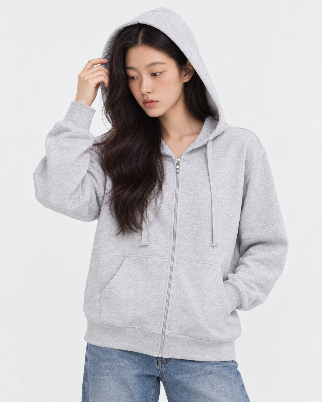 Upper body of model F03 wearing the hood of a white heather light zip-up hoodie in M, looking down