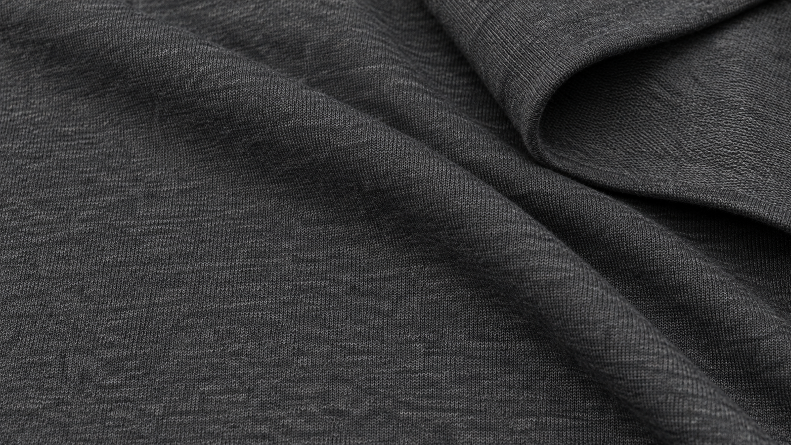 Close-up of loosely folded charcoal double-knit fabric showing the tight weave and the smooth, unbrushed inside