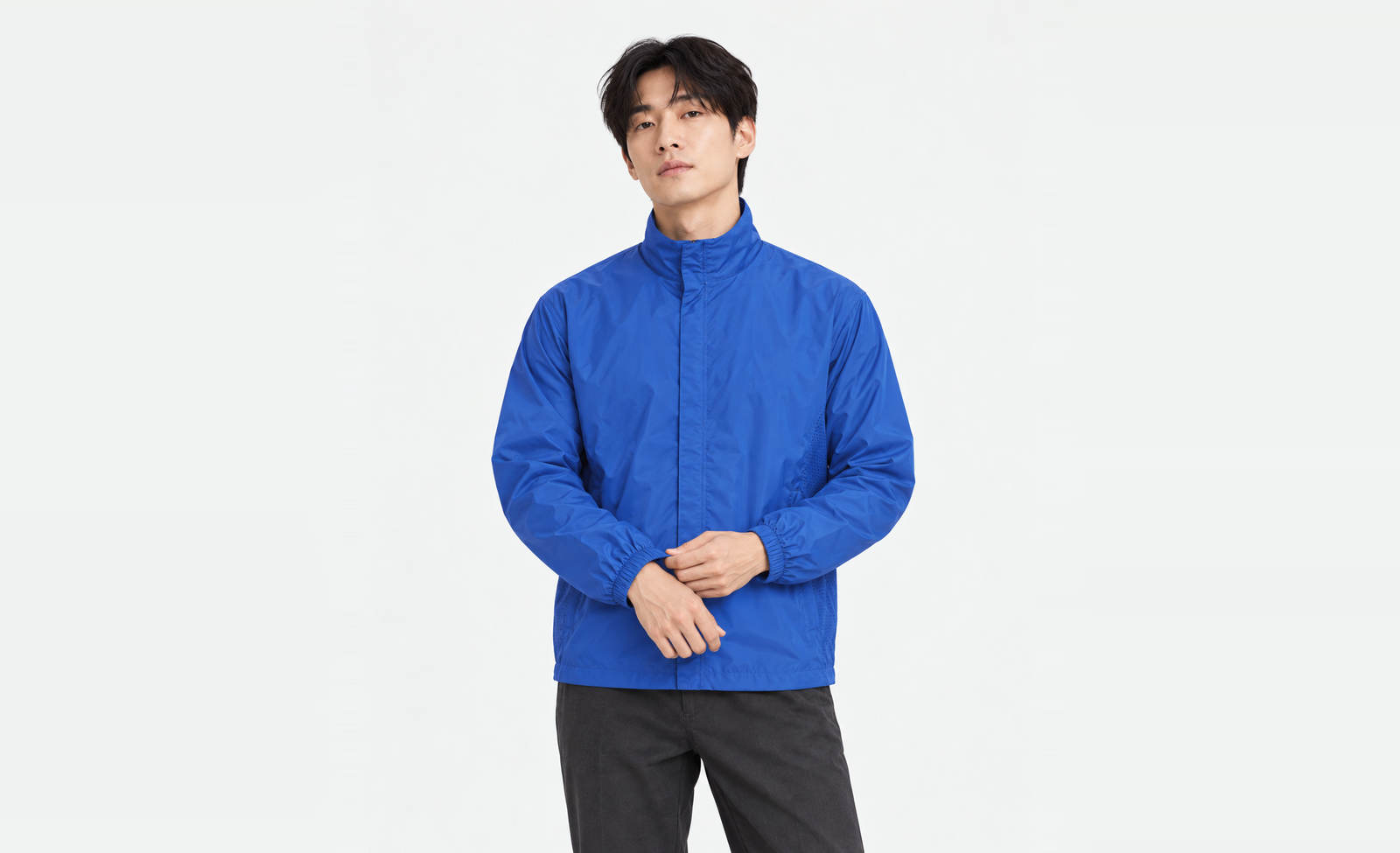 Upper body of a man in a cobalt blue basic windbreaker in L, adjusting the left elastic cuff