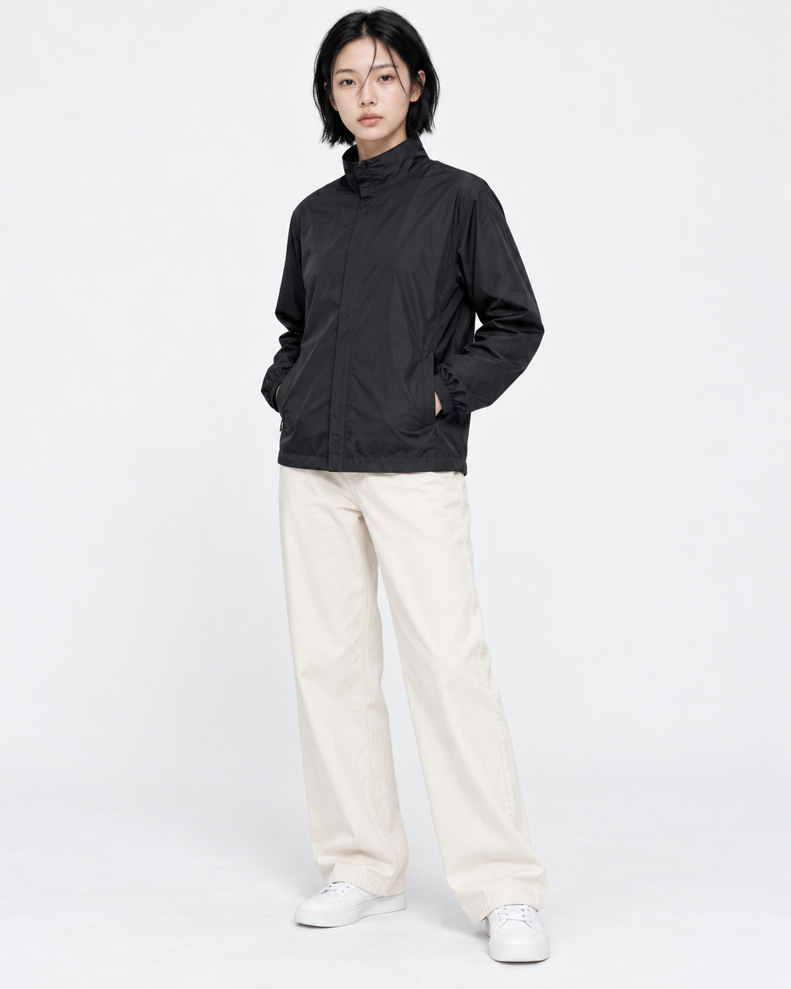 Full-length shot of a woman in a black basic windbreaker in M, both hands in the side pockets