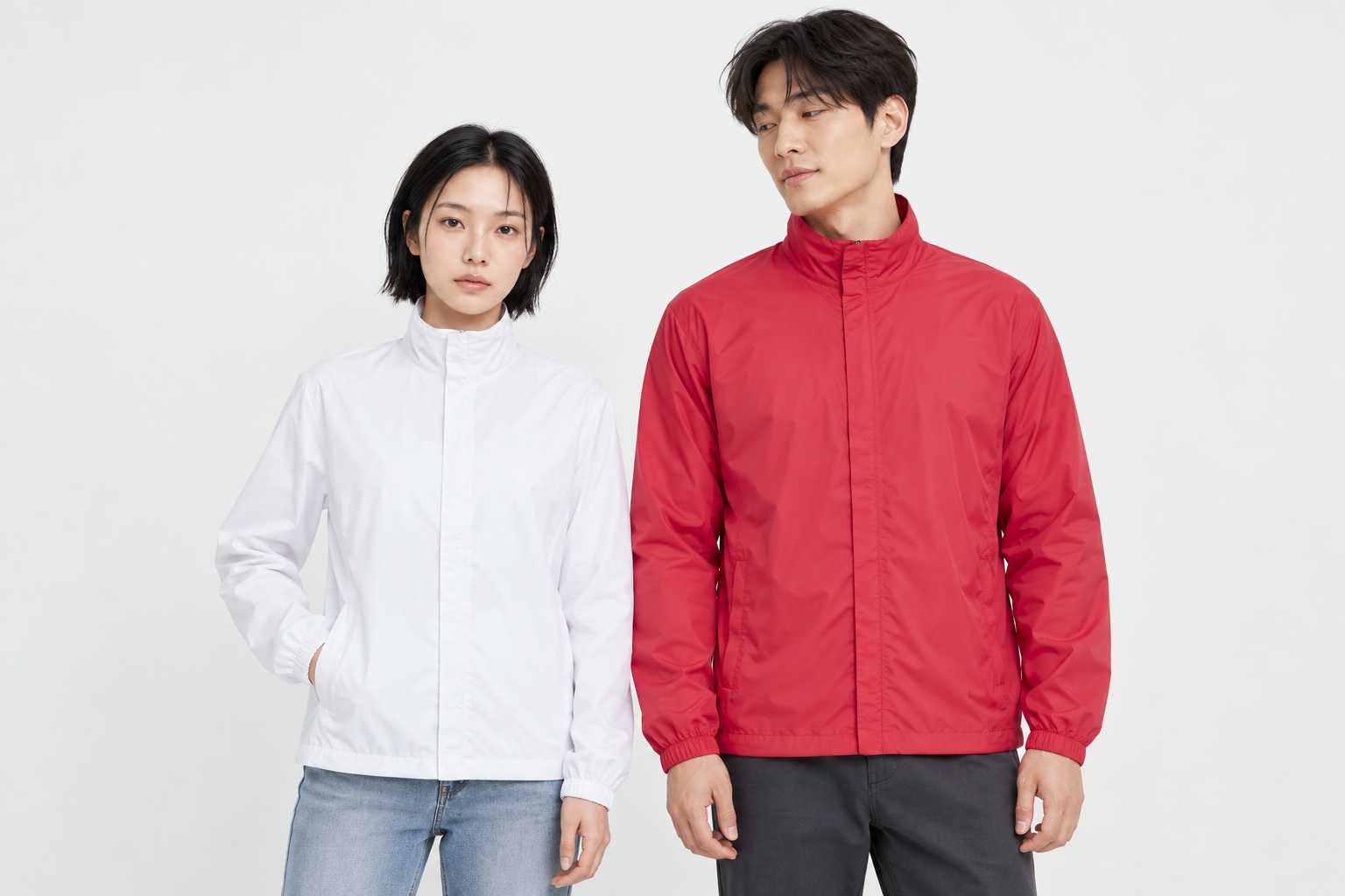 A woman in a white basic windbreaker in M and a man in red in XL turning his head toward her