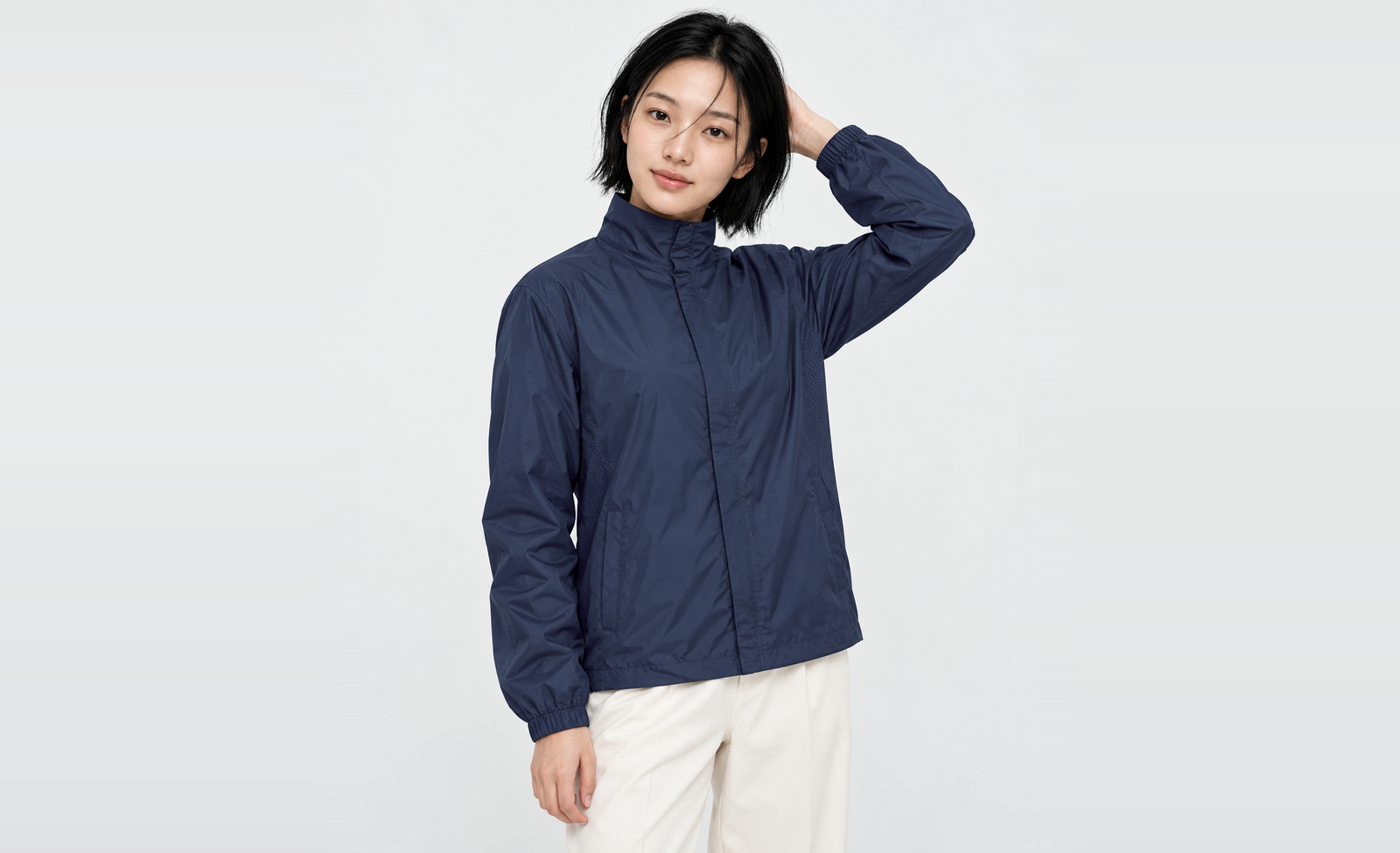 Upper body of a woman in a navy basic windbreaker in M with one hand behind her head, showing the side vent holes