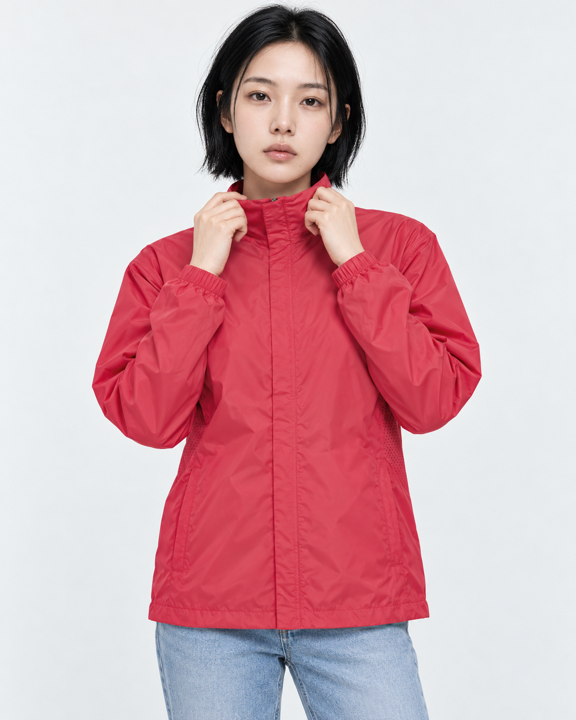 Upper body of a woman in a red basic windbreaker in M, holding the stand collar with both hands
