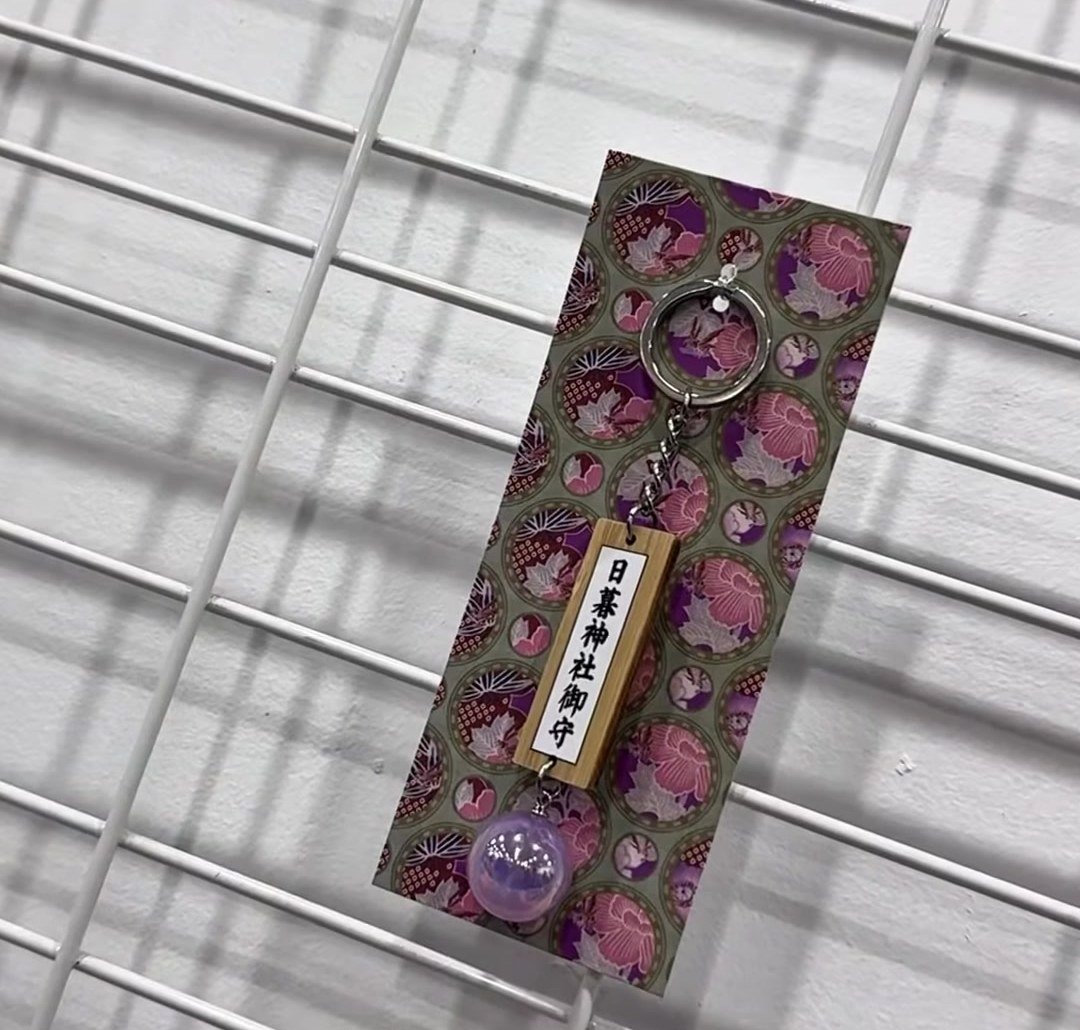 매대 옆 그물망에 걸린 에마 키링, 사혼의 구슬 장식이 달려 있다